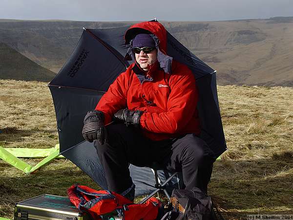 Winner John McCurdy shelters from a brief shower.