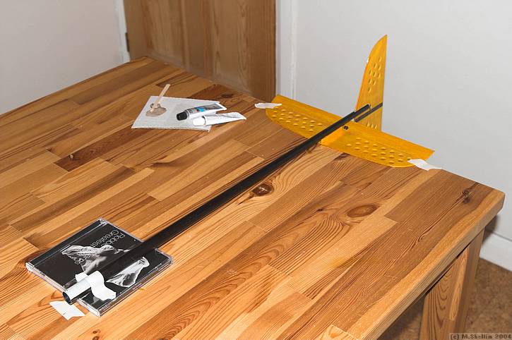 Tail feathers lined up while the epoxy sets. Masking tape holds everything square.